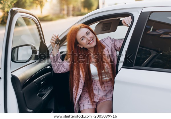 Woman bought first car. Joyful female sitting in
new car and shows keys.