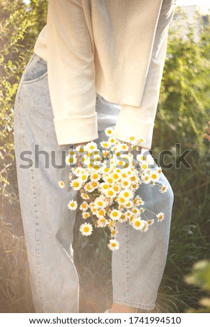 woman with a bouquet of daisies in an eco friendly net bag.