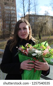Woman with a bouquet of flowers on the bridge on the background of the lake on the day of holy valentine