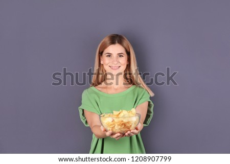 Woman with bowl of potato chips on grey background