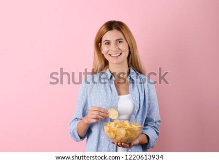 Woman with bowl of potato chips on color background