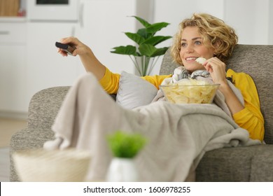 Woman With Bowl Of Potato Chips Watching Tv On Sofa