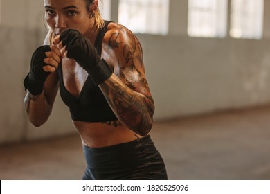 Woman boxer exercising inside a old warehouse. Female doing shadow boxing in training gym. - Powered by Shutterstock