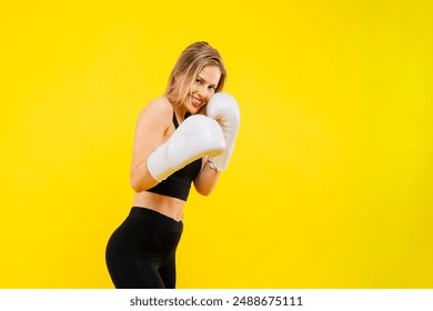 A woman boxer in gloves training on yellow background studio