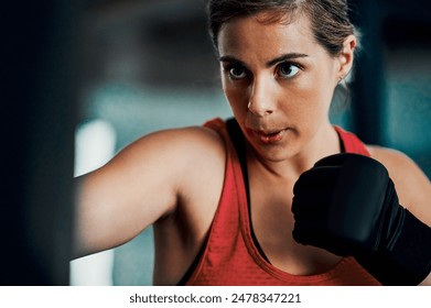 Woman, boxer and punching bag in gym for exercise, combat training with power, speed and development. Person, fighter and strong with gloves for challenge, sports and workout at martial arts club - Powered by Shutterstock