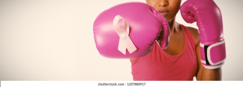 Woman with boxing gloves for breast cancer awareness with ribbon on white background - Powered by Shutterstock