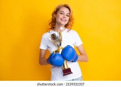 Woman in boxing gloves hold champion winner cup trophy. Winner female boxer Isolated on yellow background. Winning success power woman concept.