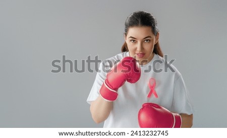 Woman in boxing gloves with a pink ribbon as a symbol of the fight against cancer. Increasing the level of knowledge about people who have overcome tumor diseases.