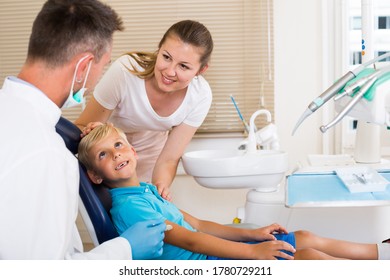 Woman with boy are visiting dentist in dental office.