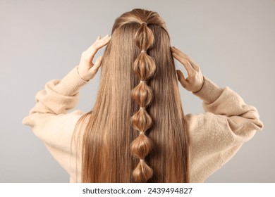 Woman with braided hair on grey background, back view - Powered by Shutterstock