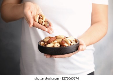 Woman With Brazil Nuts On Grey Background, Closeup