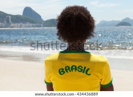 Woman in brazilian jersey looking at Sugarloaf mountain at Rio