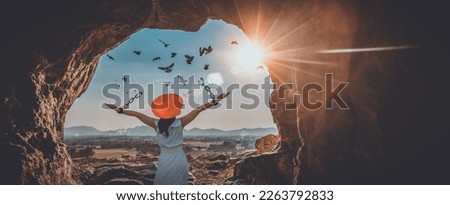 The woman is breaking the chains and setting the birds free, in a cave at the top of a mountain enjoying the nature at sunrise. concept of freedom