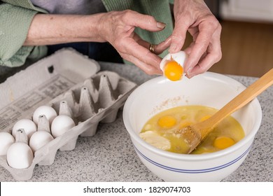 Woman breaking an egg, adding only the yolk to the other ingredients of the monkey bread. - Shutterstock ID 1829074703