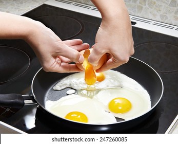 Woman Breaks An Egg In Fried Eggs Close Up