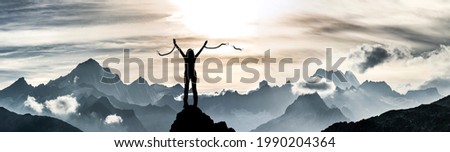 A woman breaks her chains on a mountain peak