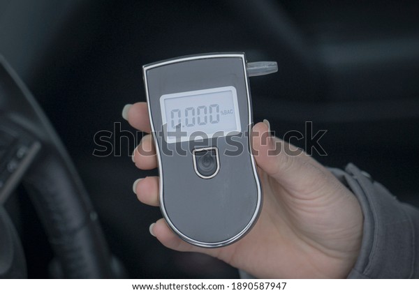 a woman with a breathalyzer in the car, testing for\
alcohol and drug intoxication of the driver, selective focusing\
tinted image