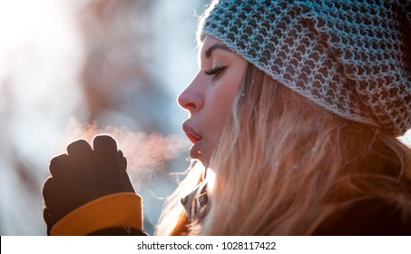 Woman Breathing On Her Hands To Keep Them Warm At Cold Winter Day