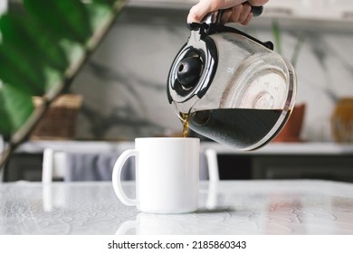 Woman brewed coffee and pours it into a mug for breakfast.