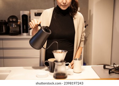 A woman brewing coffee in her kitchen at home - Powered by Shutterstock