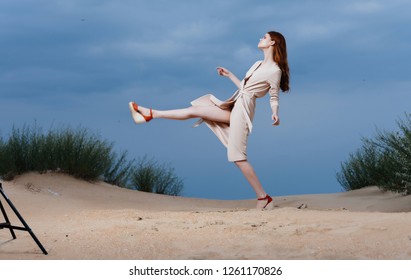 A Woman In Bright Clothes Makes A Big Step In The Sand 