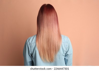 Woman and bright dyed hair pale pink background  back view