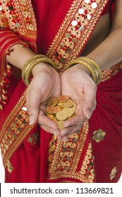 Woman in bright red mekhla holding gold coins