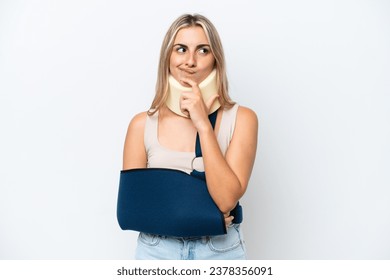 Woman with broken arm and wearing a sling isolated on white background having doubts and thinking