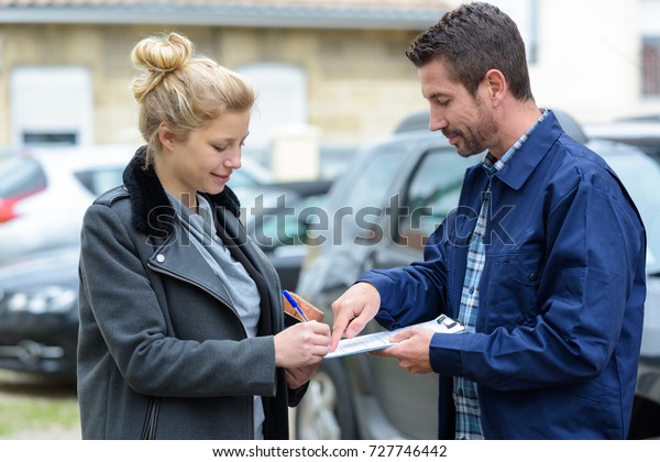 woman with broken car\
signing paperwork