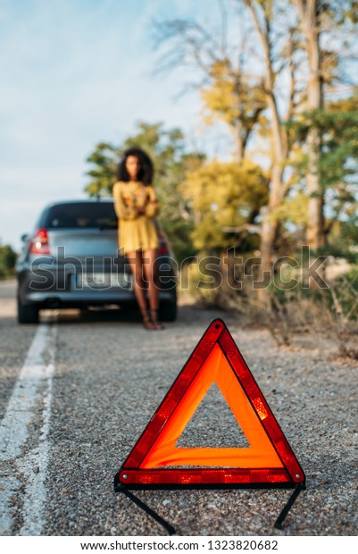 Woman with broken car and\
triangle