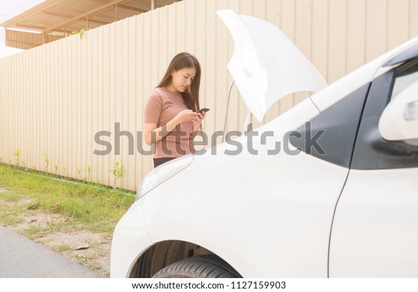 Woman and broken down car on\
street, Woman using mobile phone near a broken car, Auto\
Concept
