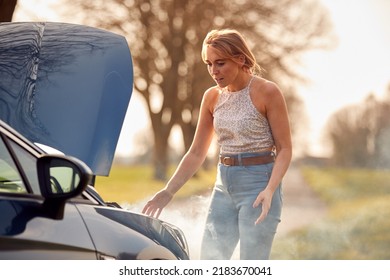 Woman Broken Down On Country Road Looking Under Smoking Bonnet Of Car