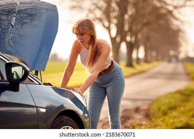 Woman Broken Down On Country Road Looking Under Bonnet Of Car