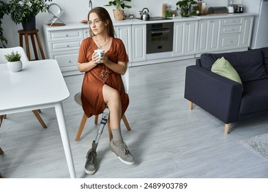 Woman in brown dress sits in modern kitchen chair, holding coffee with visible prosthetic leg - Powered by Shutterstock