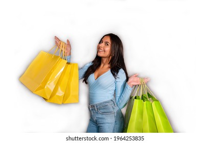 Woman with brown hair, blue jeans and jersey holds yellow and green shopping bags.