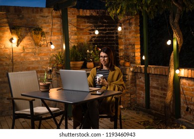 Woman Browsing News In Her Backyard. Night Scene.