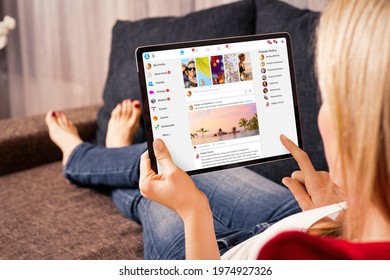 Woman browsing social media website on tablet computer at home