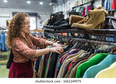 Woman Browsing Through Vintage Clothing In A Thrift Store.