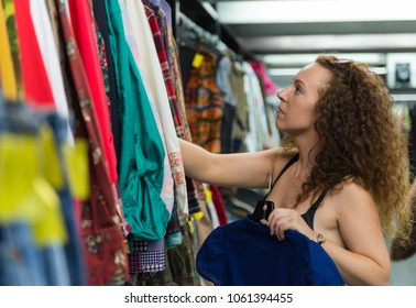 Woman Browsing Through Vintage Clothing In A Thrift Store.