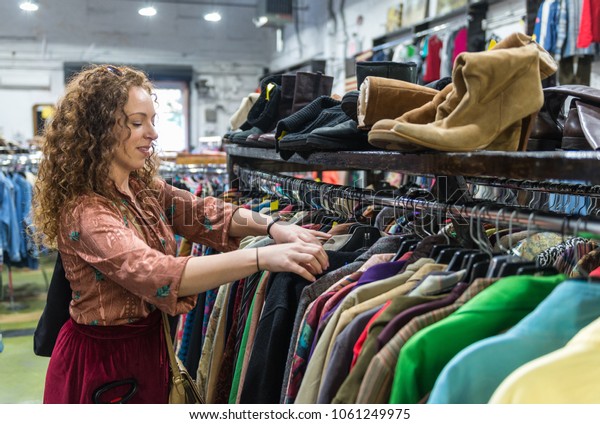 Woman browsing through vintage clothing in a\
Thrift Store.