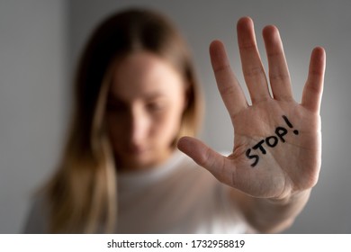 Woman with bruises on her face showing stop sign, palm in focus