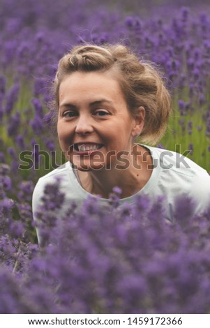 Woman with brunette hair smiles while posing in a field of lavender flowers in Sequim Washington