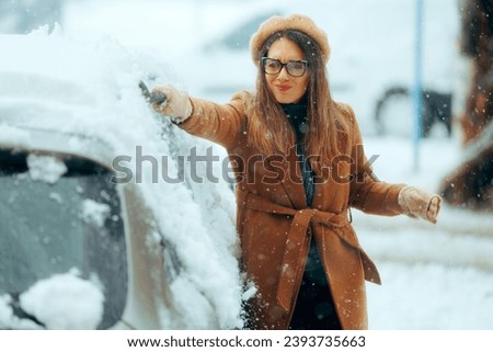 
Woman with a Brush Removing snow from her Car After Blizzard 
Person using a snow broom to uncover her vehicle from a trip
