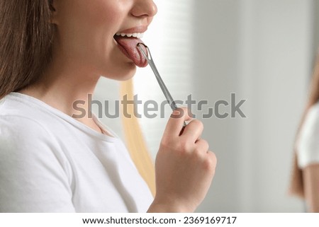 Woman brushing her tongue with cleaner on blurred background, closeup. Space for text