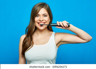 Woman brushing teeth with electric toothbrush. Blue background.