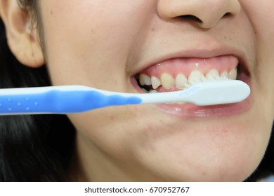 woman brushing teeth with toothbrush