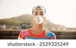 Woman, bubble gum and portrait in city, summer and trendy style with chewing, candy and outdoor in street. Girl, persona and sweets with fashion, streetwear and attitude on metro bridge in Colombia