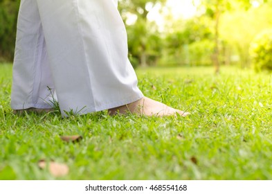 Woman Buddhist Walking On Green Grass For Relaxation And Meditation Over Sunlight