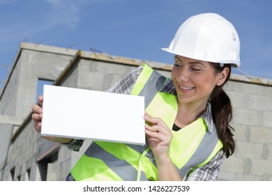 woman in a building helmet shows an empty banner - Powered by Shutterstock