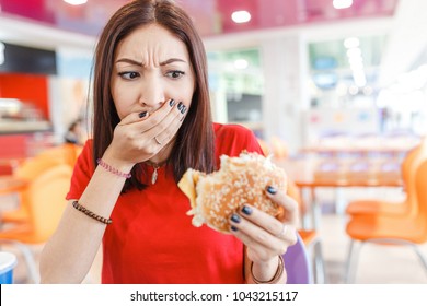 Woman With Burger In Hand, Making Bad And Disgusting Face, Concept Of The Bad Spoiled Food And Problems With Digestion